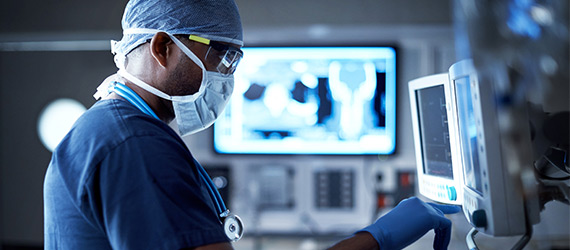 surgeon in ppe looking at medical equipment